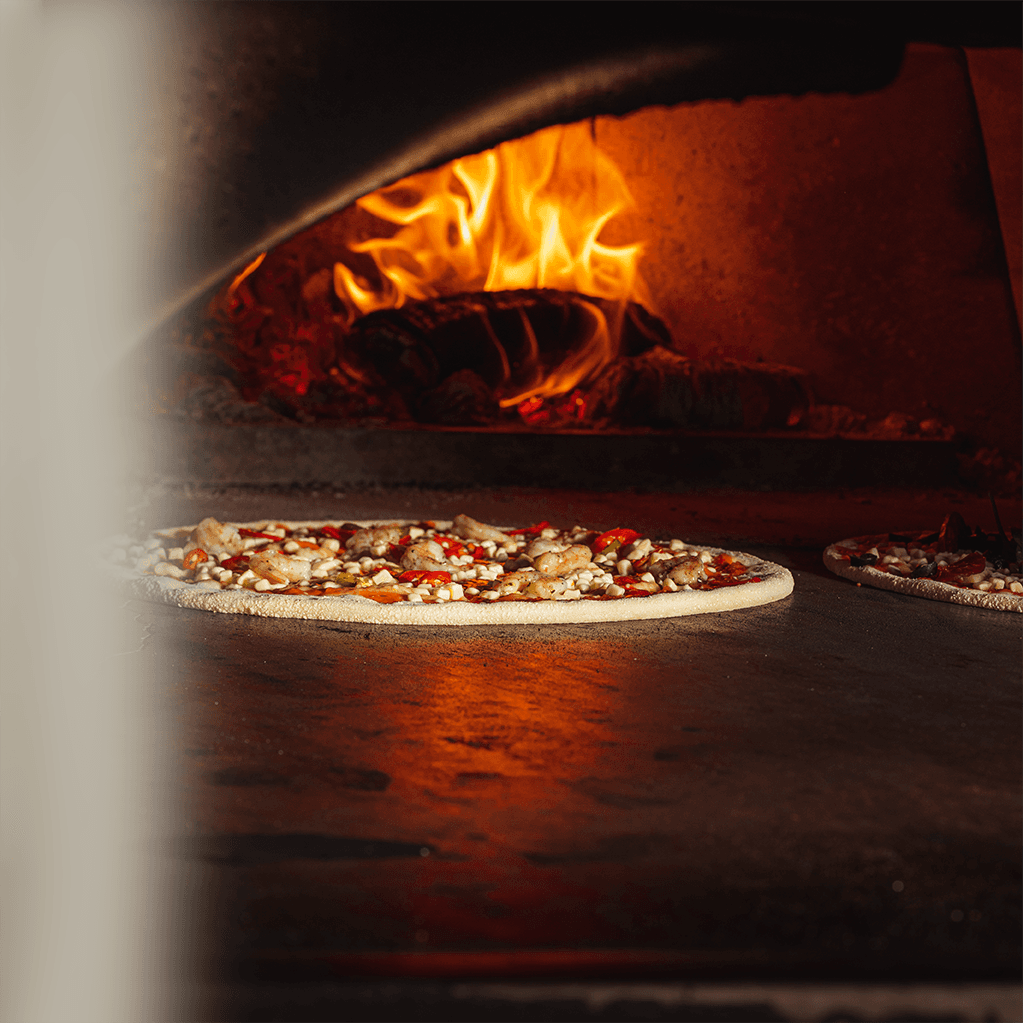 A pizza baking in the wood fired oven