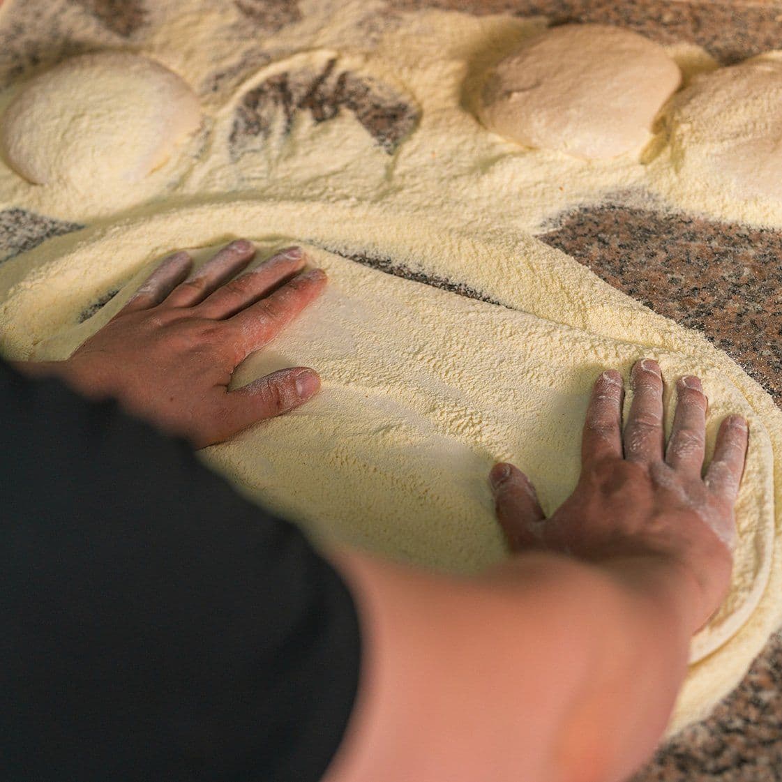 Pizza dough being hand-stretched